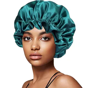 Detailed view of elastic ruffled edge and smooth satin fabric on dark green sleep bonnet