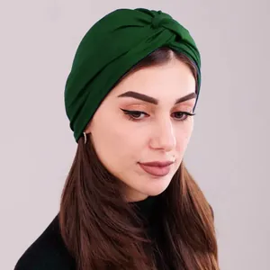 Detail of dark green twisted turban cap showing crisscross design and soft fabric texture