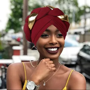 Detail of burgundy ribbed turban with golden metallic braided twist on street model