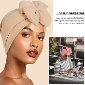 Elegant stretch turban hat with large bow and pleated design in beige and pink tones