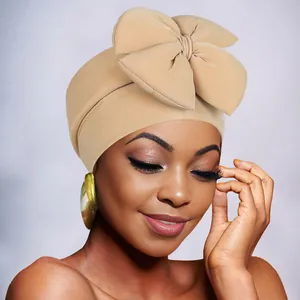 Detail shot of a khaki stretchy turban featuring a large fashionable 3D bow design