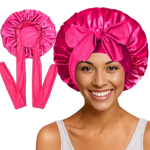 Détail du bonnet en satin rose avec de larges rubans et un grand nœud ajustable