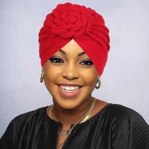Close-up of red knit turban hat featuring large handmade braided flower design