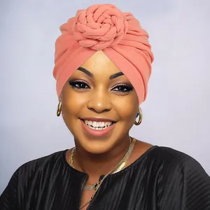 Close-up of coral knit turban hat featuring a spiral flower knot and soft texture