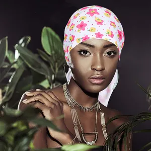 Detail van een gebloemde hoofddoek in zijdeachtig wit materiaal met roze bloemen en stippen
