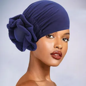 Detail of navy blue pleated turban hat featuring a large decorative side flower for women