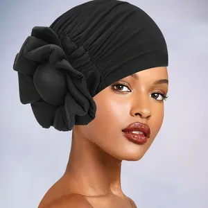 Detail view of the side-mounted large fabric flower on the pleated black turban cap