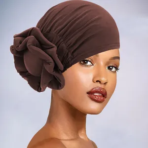Detail of dark brown turban cap with large side flower and elastic pleated texture