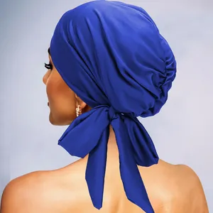 Détail du turban en satin bleu roi montrant la texture plissée et le nœud papillon arrière