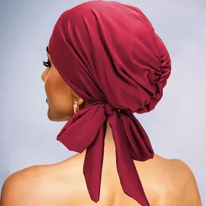 Détail du turban en satin bordeaux avec grand nœud décoratif et plis élastiques à l'arrière