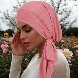 Pink ribbed headscarf with cross front and long ties in an elegant outdoor setting