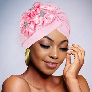 Close-up of pink turban cap with satin flower decorations and shiny mesh fabric