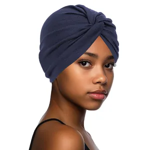 Close-up of navy blue turban hat showing the cross-knot design and elastic knit fabric texture