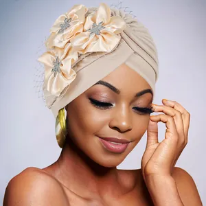 Detail of beige pleated turban with satin flowers, silver rhinestones and black mesh veil