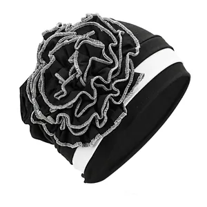 Close-up of contrast black and white turban hat with large side flower and stitching detail