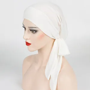 Side view of white cross-front turban with elastic ribbed texture and long adjustable ties
