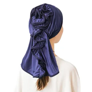 Detail of navy blue satin turban with 3D floral petals and long wavy pleated ribbons