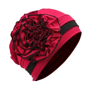 Detail of red turban hat with 3D floral accent and black contrast edging