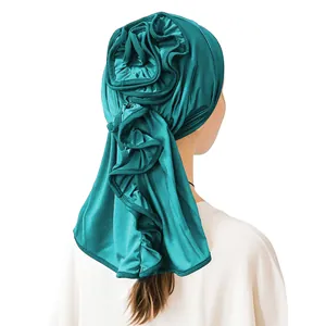 Detail of teal satin turban showing 3D floral folds and elegant cascading ruffles