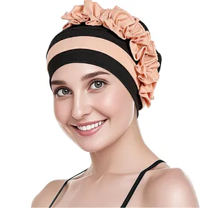 Dettaglio del turbante plissettato nero e rosa corallo con grande decorazione a balze
