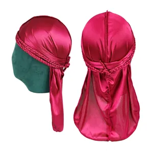 Rose red silky durag with braided band and long tail shown on a green mannequin