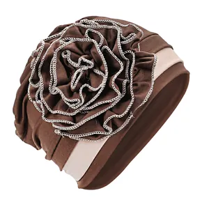 Close-up of brown turban hat featuring a large floral detail with white stitched edges