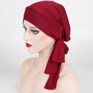 Detail of burgundy ribbed turban with front cross knot and long tail on a model head