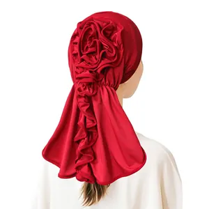 Rear view of red milk silk turban with large 3D flower and ruffled pleated hem details