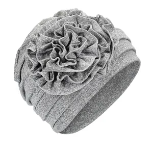 Close-up of a grey stretch turban hat featuring a large layered ruffle flower detail
