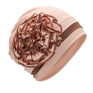 Detail of pink turban hat with a large side flower featuring brown contrast edges