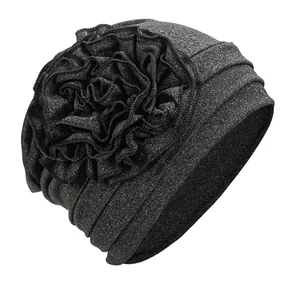 Detailed close-up of charcoal gray turban cap with layered fabric flower decoration