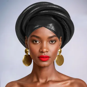 Detail of black textured Gele headwrap paired with large gold geometric disc earrings