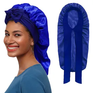 Detail of royal blue satin sleep bonnet featuring a front bow and long tail for hair care