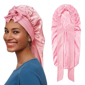 Detail of pink satin sleep bonnet featuring a large decorative bow and long ribbon tail