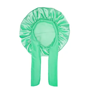 Detail of mint green satin sleep bonnet featuring long adjustable straps and smooth texture