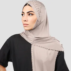 Detalle de un elegante hiyab color topo con adornos de perlas y pedrería brillante