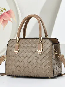 Sac à main tissé en cuir marron avec fermoir doré et bandoulière sur fond blanc épuré