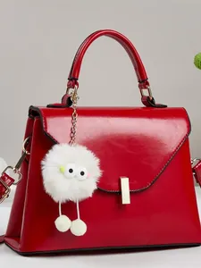 Elegante hellrote Lackleder-Handtasche mit Goldschloss und flauschigem Monster-Anhänger