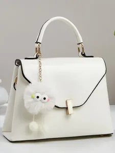 Weiße minimalistische Tasche mit goldenem Verschluss und süßem Monster-Plüschanhänger