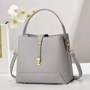 Detail of grey lychee leather handbag with gold metal clasp and orchid decor