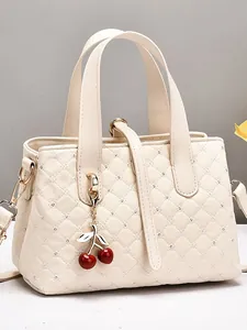 Elegant beige quilted handbag with diamond accents, cherry charm, and gold hardware