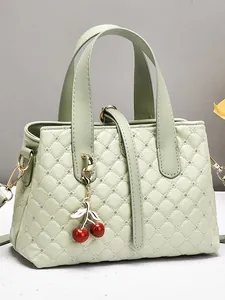 Light green quilted bridal handbag with rhinestone studs and cherry charm on gray background