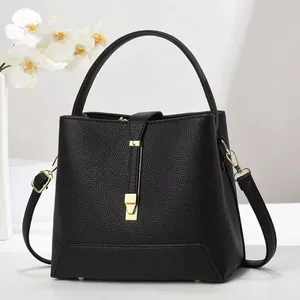 Detail of black lychee leather handbag featuring golden metal hardware and white orchid decor