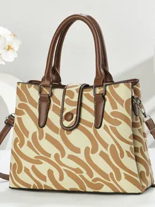 Beige canvas handbag with brown geometric prints and adjustable leather shoulder strap