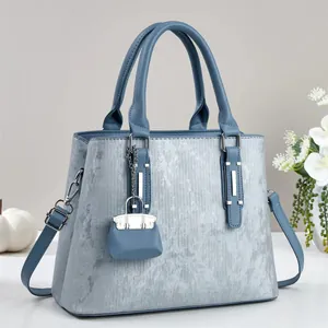 Detail view of a light blue tote bag with metallic sheen, silver hardware, and shoulder strap