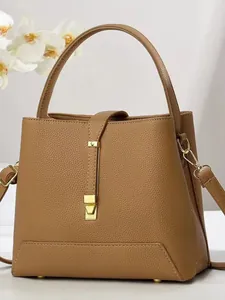 Brown lychee leather bucket bag for women with gold clasp and elegant orchid backdrop