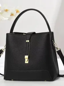 Minimalist black leather bucket bag with litchi texture and gold metal buckle detail