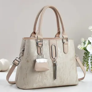 Detail van beige shopper met textuurmateriaal, metalen ringen en een kwastje