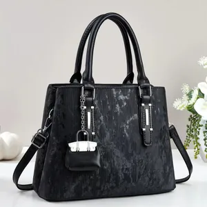 Detail of black marble textured tote bag with silver hardware and mini pouch charm