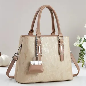 Detail of metallic silk texture tote bag with leather strap and mini charm hanging